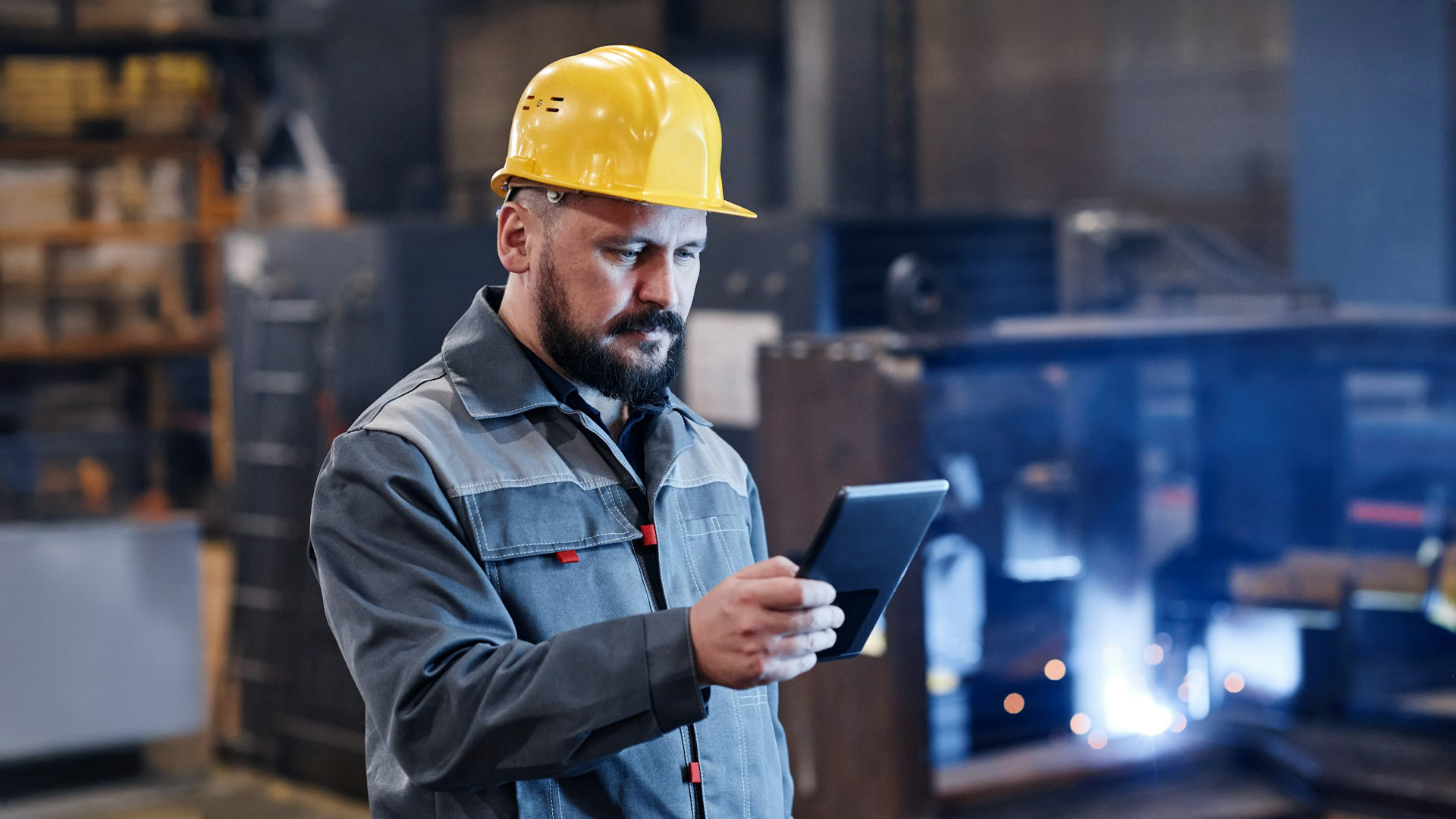 Male engineer or builder in workwear using tablet for checking data about goods